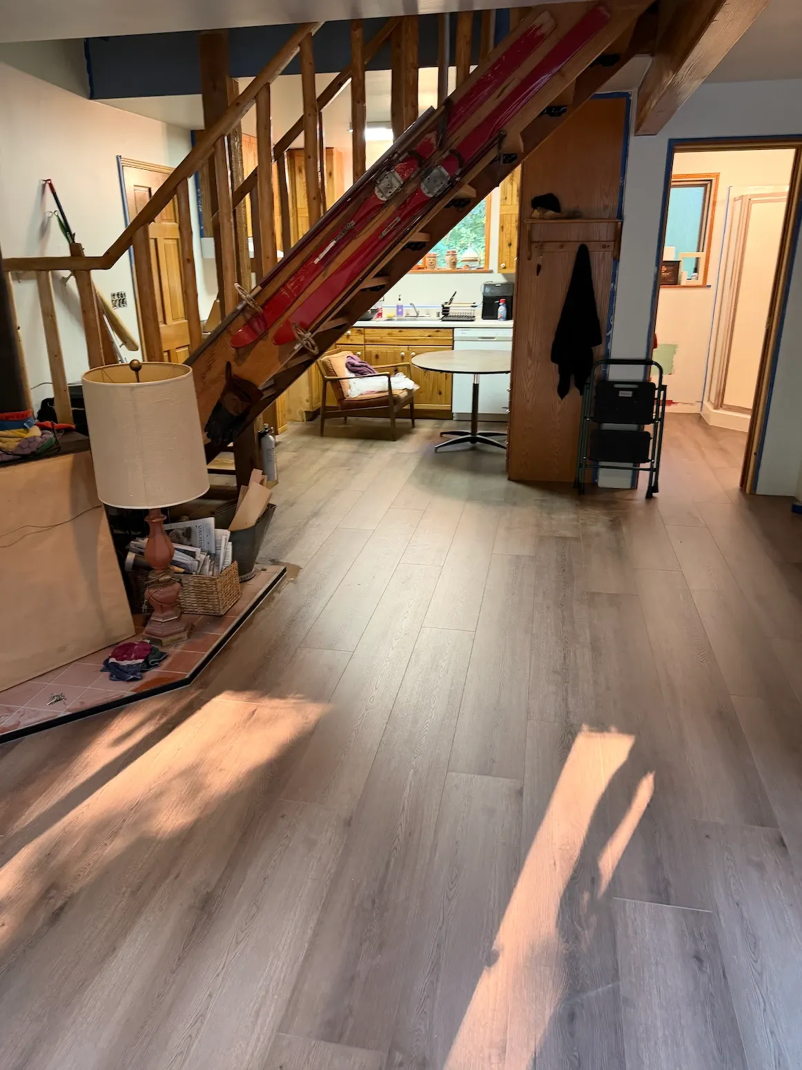 Gray-brown wood-look vinyl plank around a tiled hearth under an open wood staircase