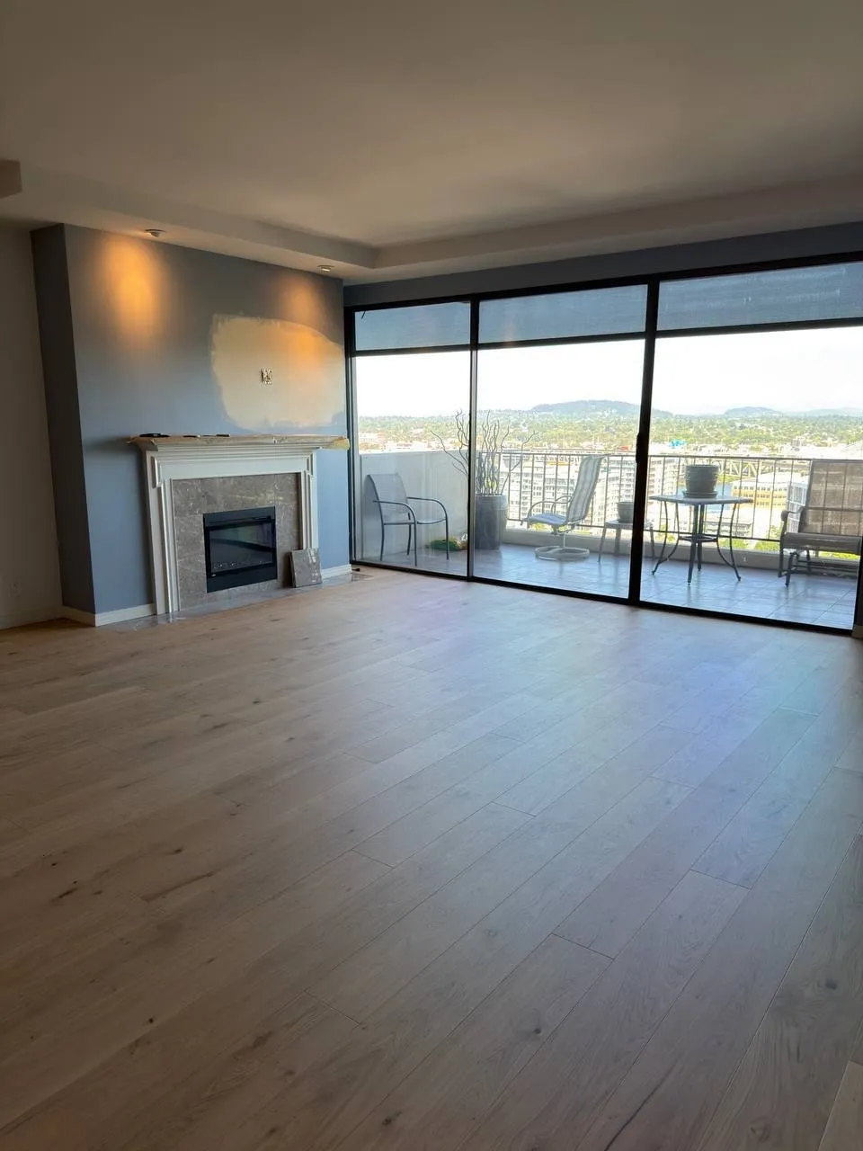 Wood-look plank floor in a living room with a fireplace and sliding doors to a view deck