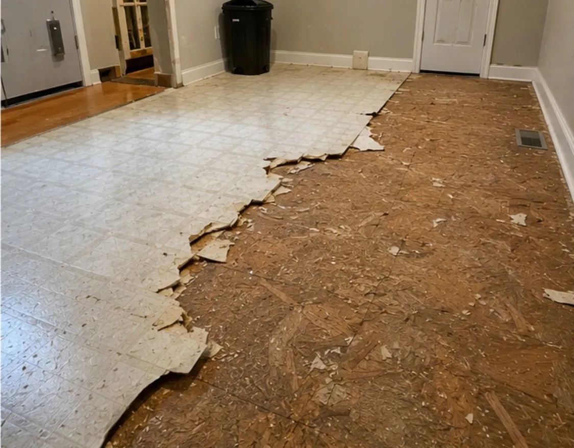 Old vinyl floor tiles being removed down to the wood subfloor